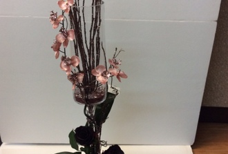vase sur pied avec orchidé rose et a`la base de roses